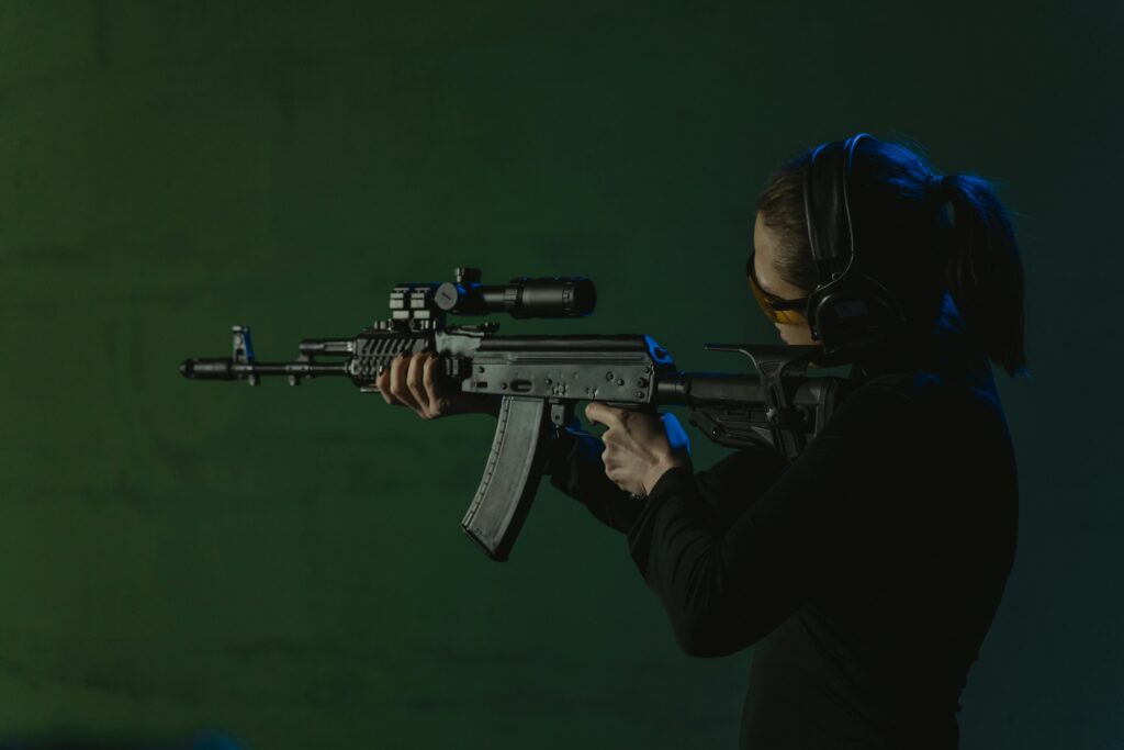 Woman holding a gun and pointing at target in low light. 